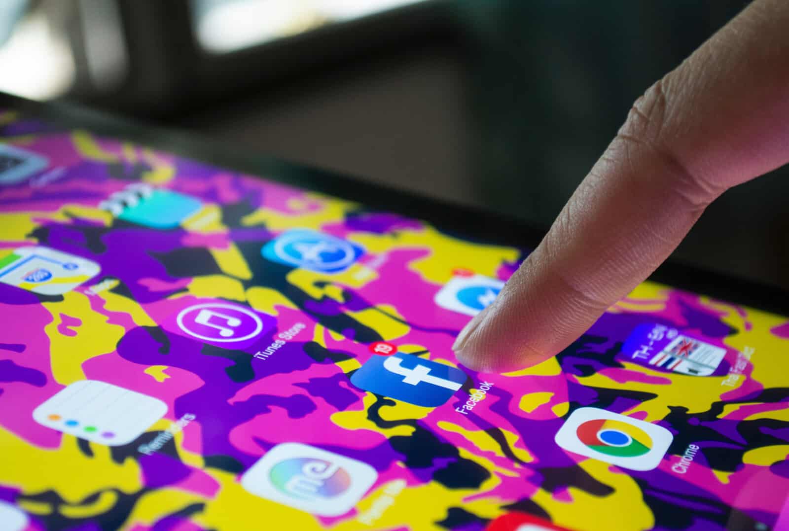 A person is pointing at a tablet with a colorful design.